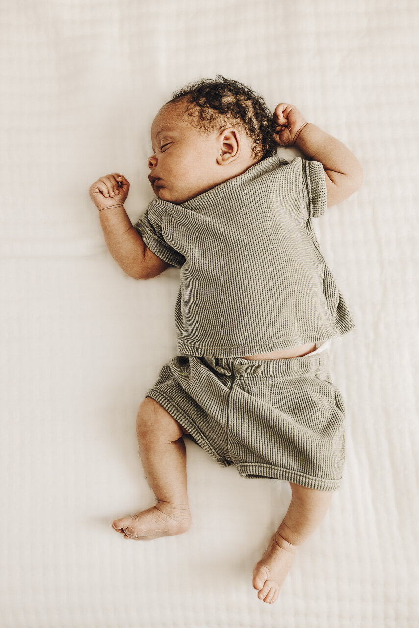 Looking down on newborn boy sleeping in green outfit: lifestyle newborn photography in Statesboro