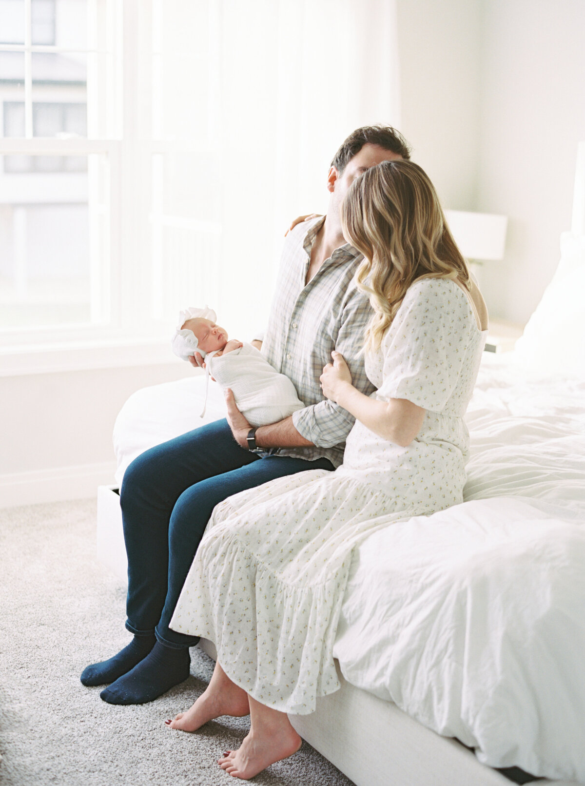 parents in master bedroom holding new baby girl by photographer in madison wi talia laird photography