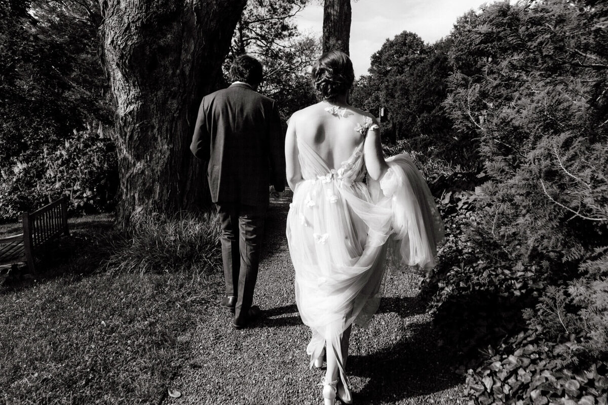 Back view of the bride and the groom while walking at a garden