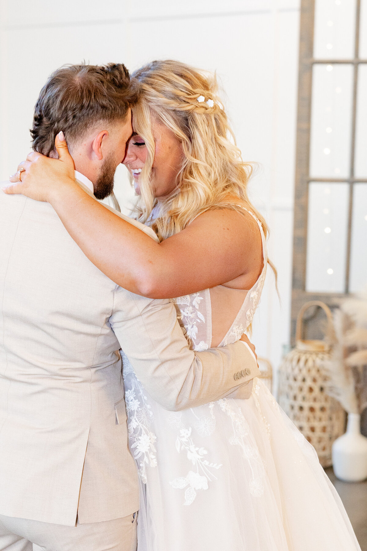 The couple embraces during their first dance, smiling warmly as they look into each other’s eyes.