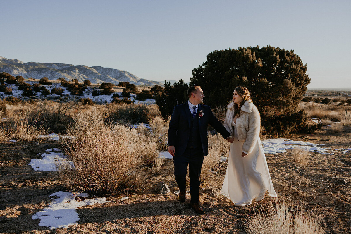 bride and groom walking together in the desert