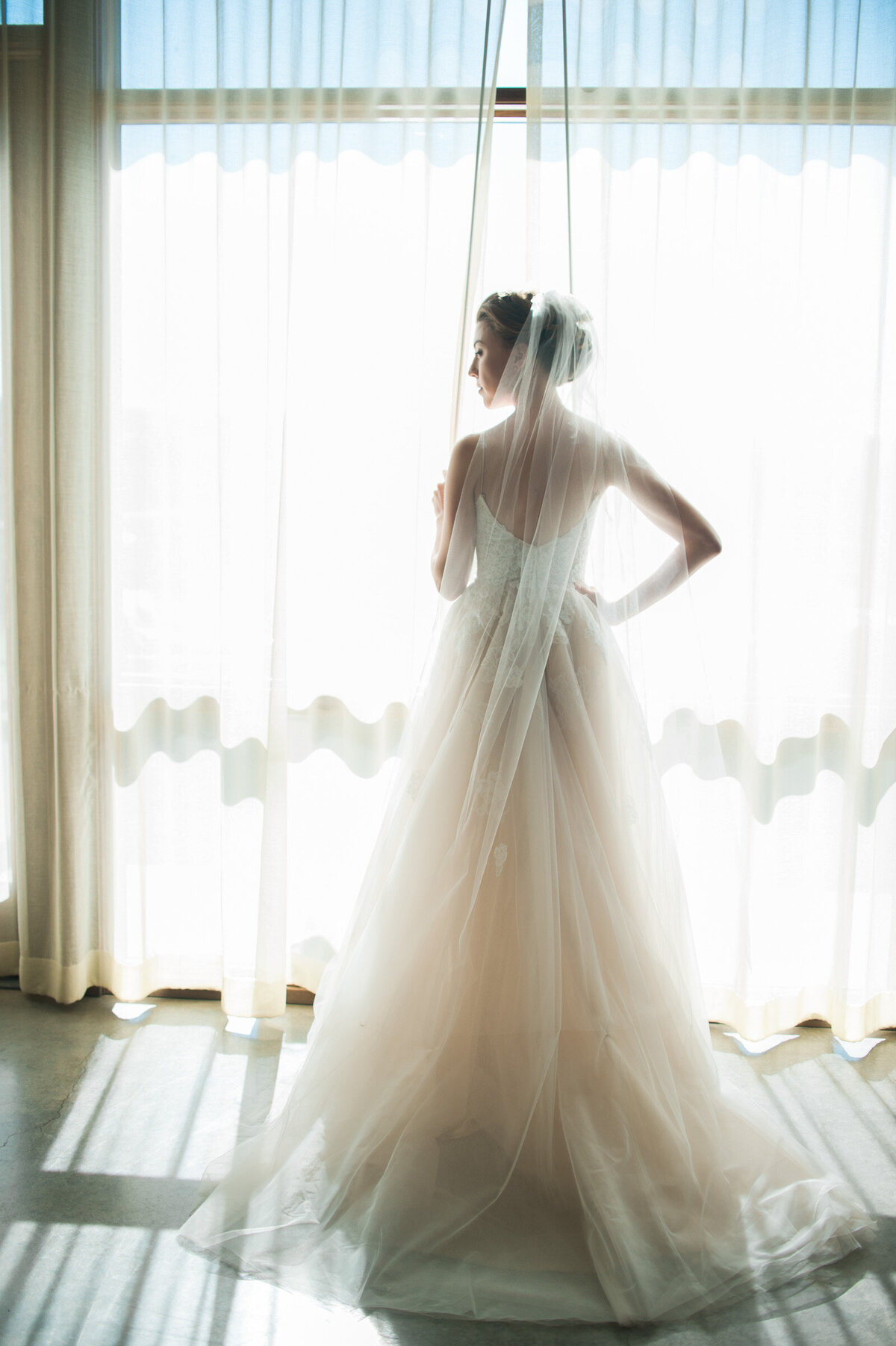 luxury bride in front of windows at ponzi winery in the bridal suite