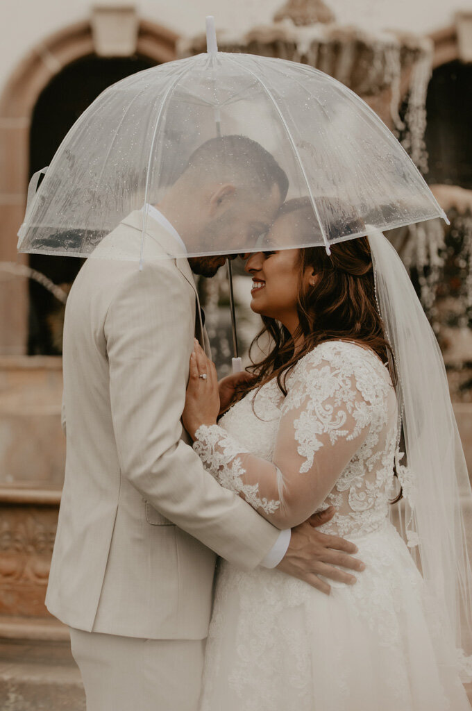 Bride and groom embracing under umbrella