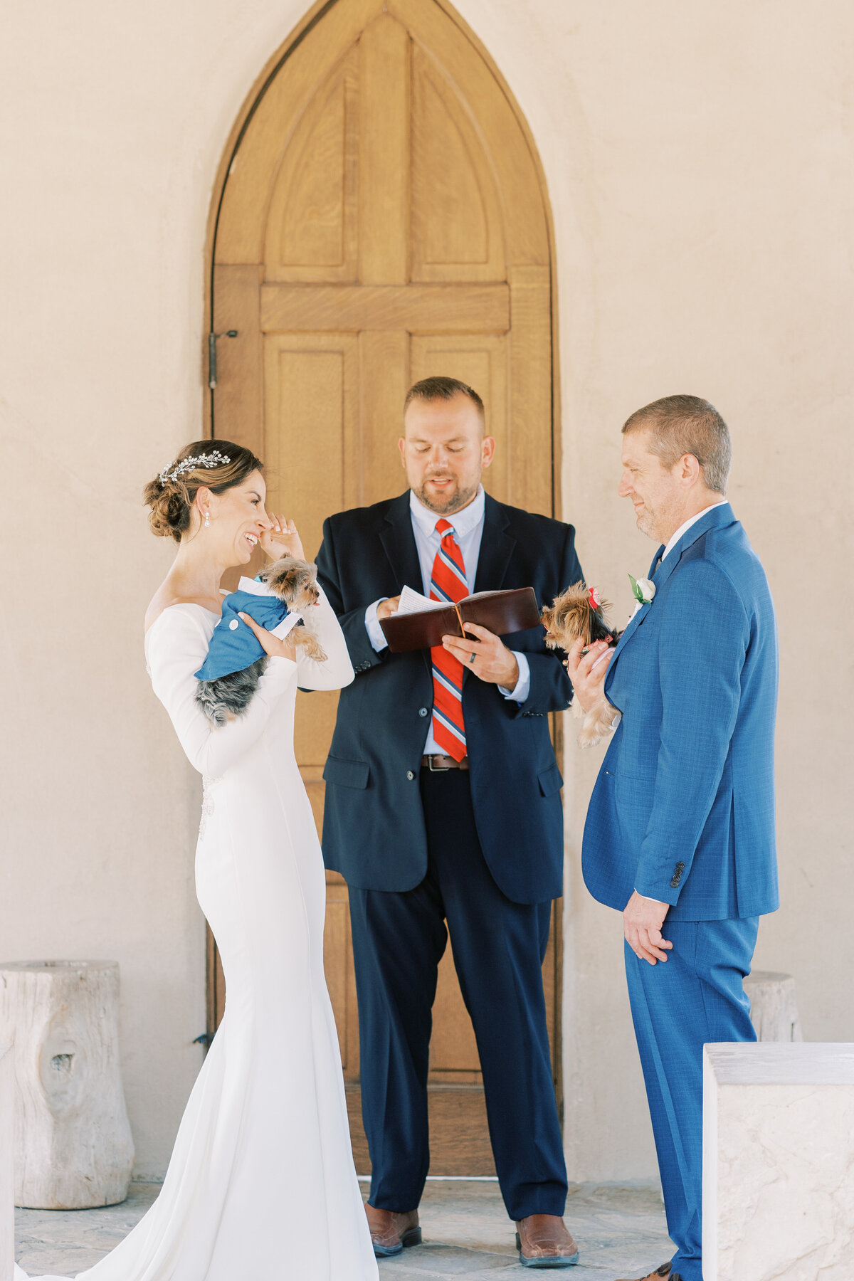 Couple getting married in a chapel. The couple is holding puppies on their hands while getting married