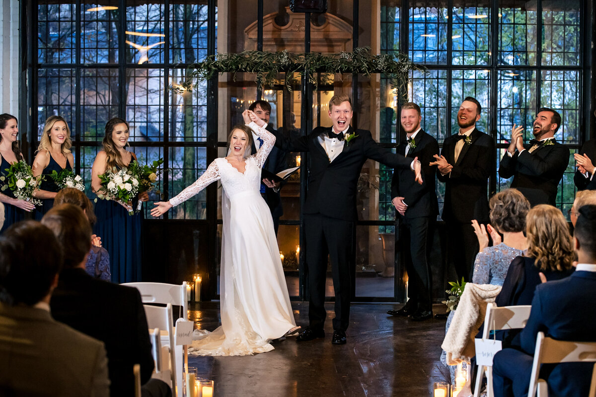 Bride and groom cheering after being announced as husband and wife during their ceremony at the Westside Warehouse in Atlanta, GA by Charlotte wedding photographers DeLong Photography