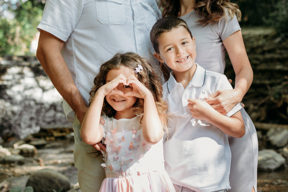 kids enjoying their parents embrace during a family photoshoot in SOuth ELgin, IL by a creek