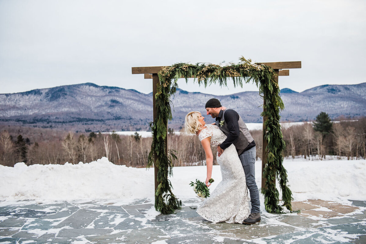 elopement couple kissing in front of arbor at winter elopement in chittenden vermont at mountain top inn