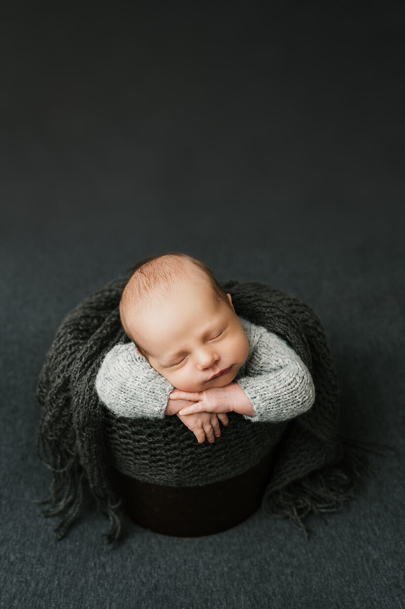 Sleeping baby in a bucket wrapped in dark gray