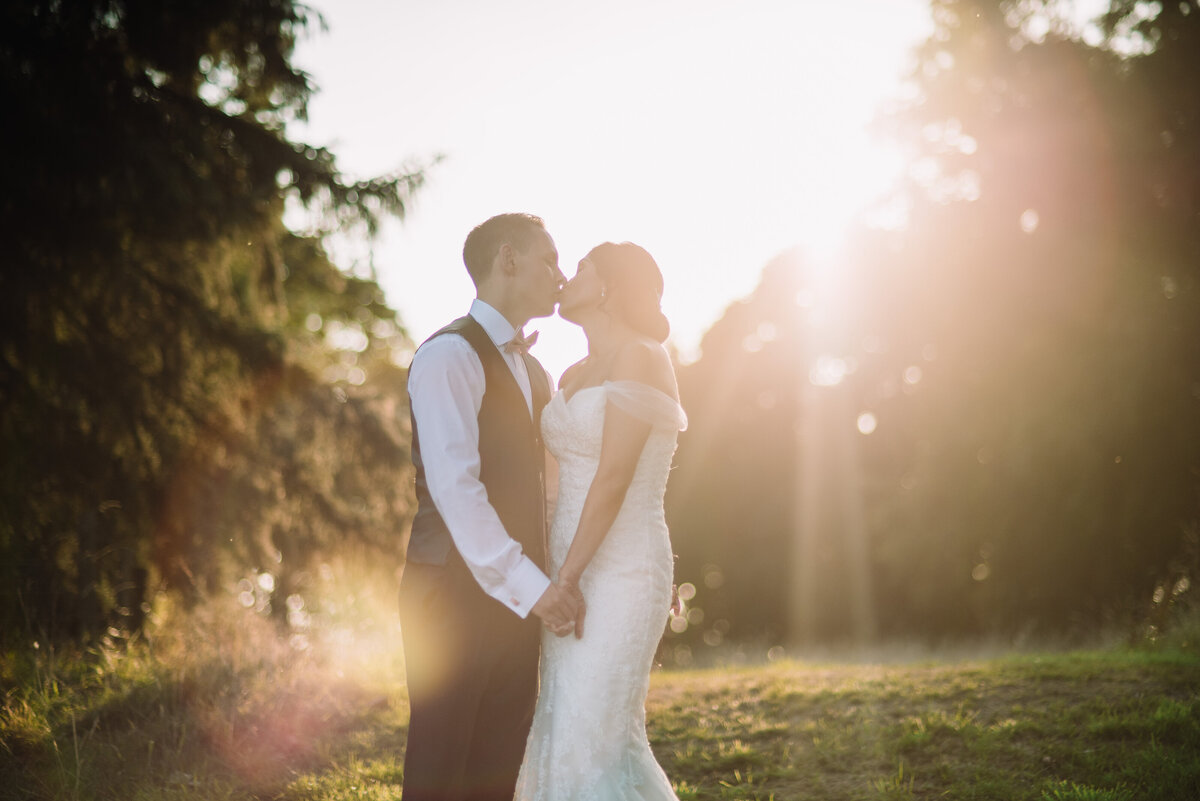 A newly married couple sharing a kiss at sunset in a woodland area taken by London Wedding Photographer Liberty Pearl