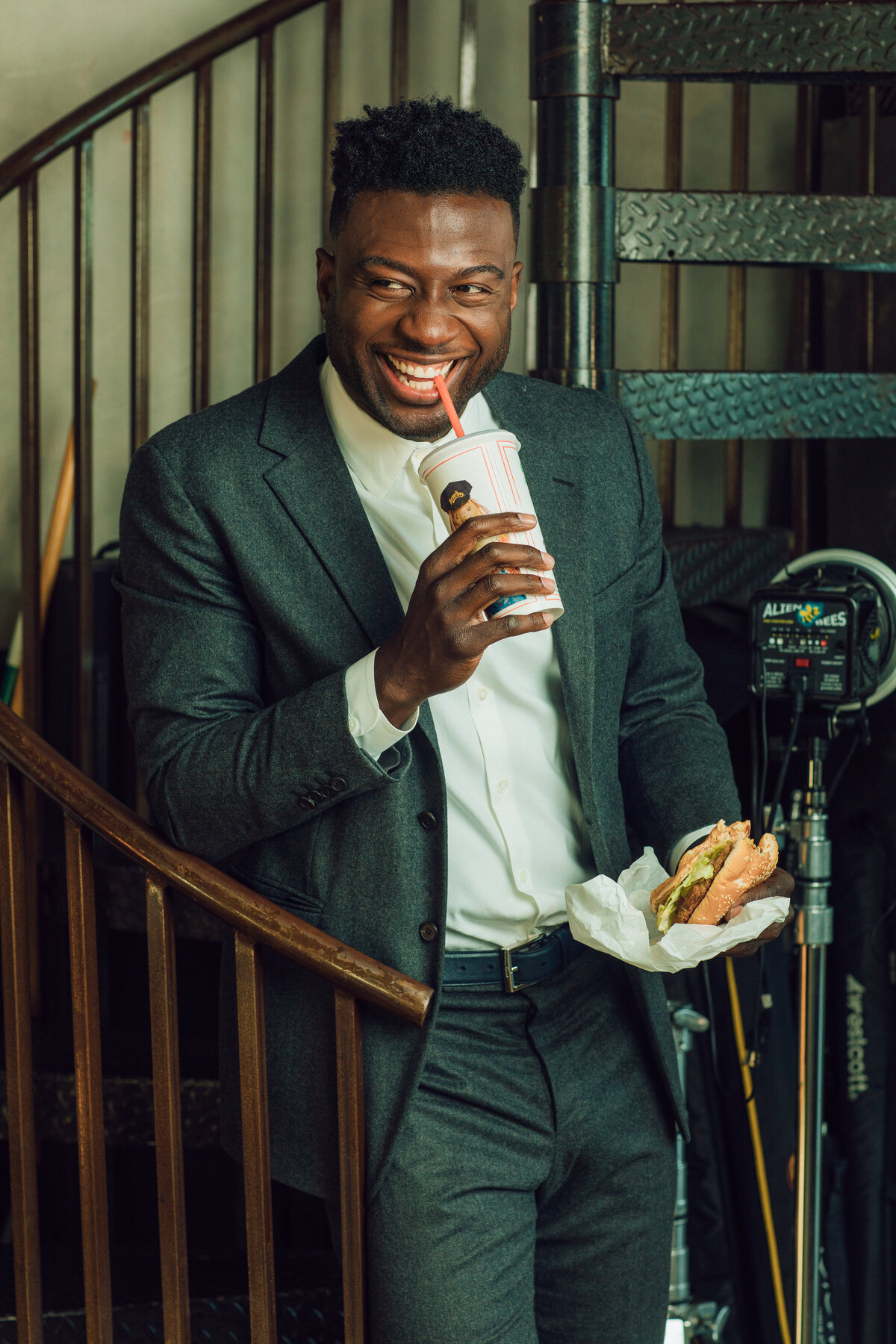 Portrait Photo Of Young Black Man In Suit Laughing While Sipping a Drink Los Angeles