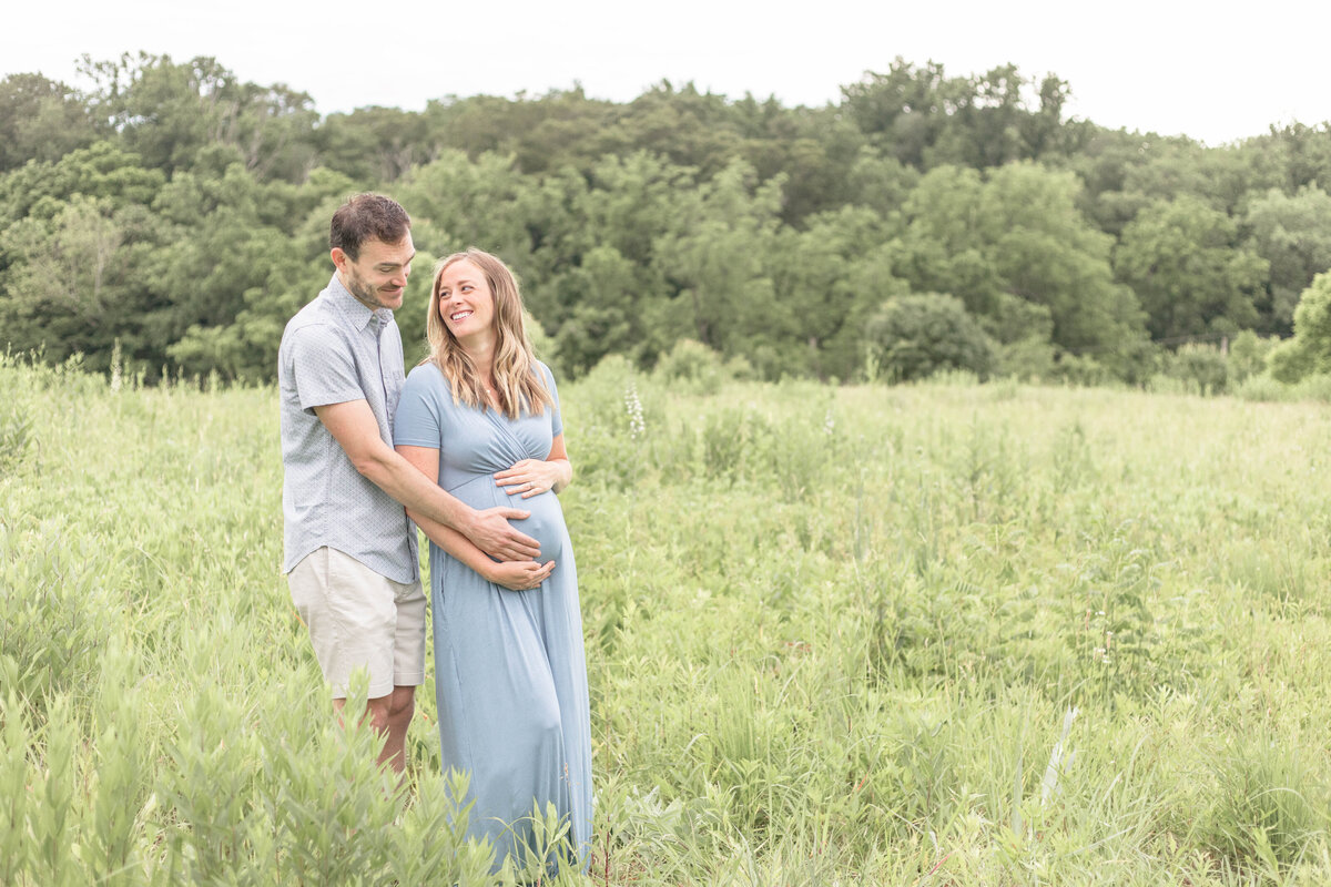 French Park Cincinnati Maternity Session Mom and Dad snuggling in a green field