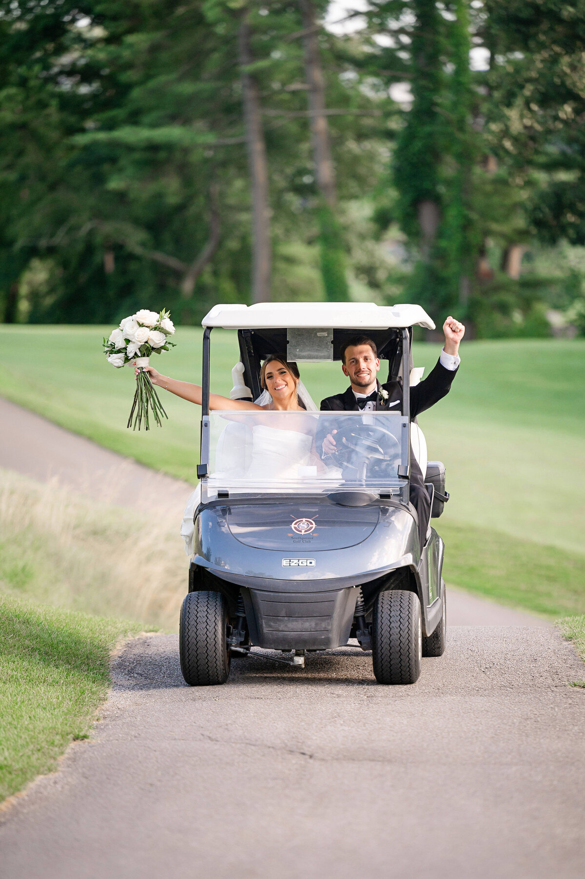 bride and groom cheering as they ride on a golf cart