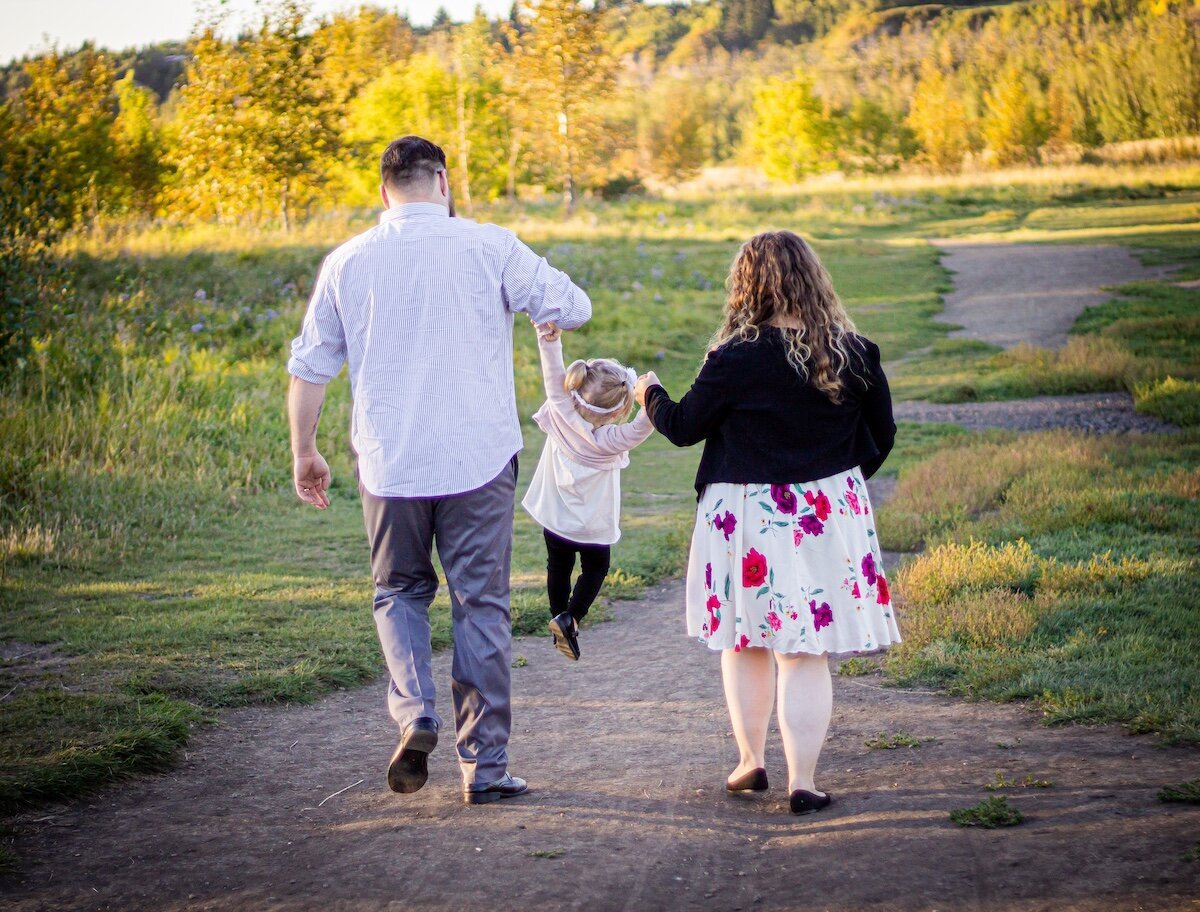 an Edmonton couple swing their toddler daughter into the air on a dirt road