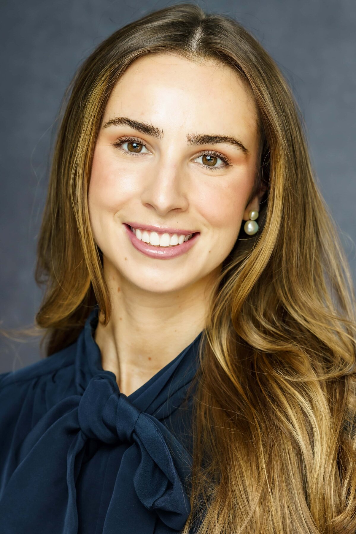 Portrait of a young woman smiling with long hair and a dark blouse 