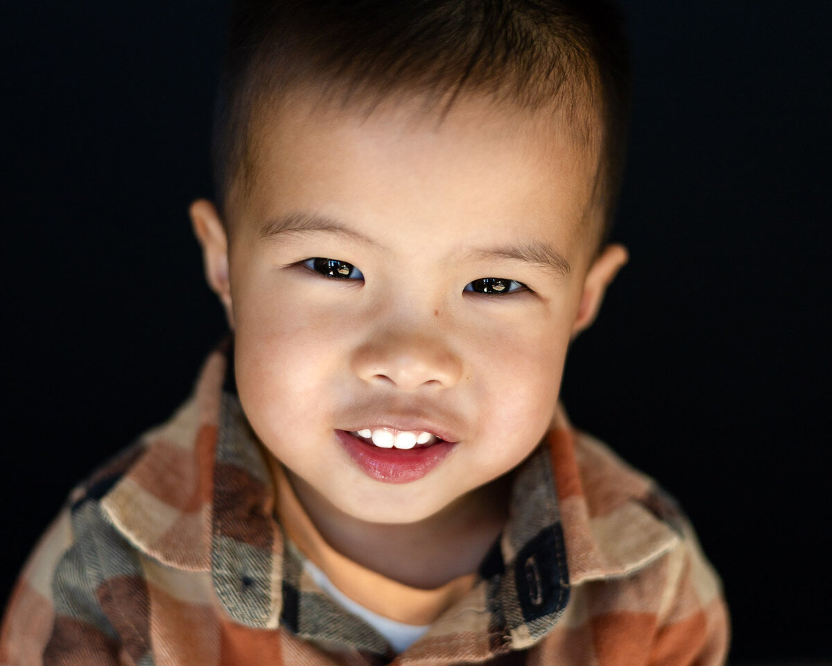 Young student smiling brightly against a dark background during Bay Area School Photography session – Ellobelle Photography