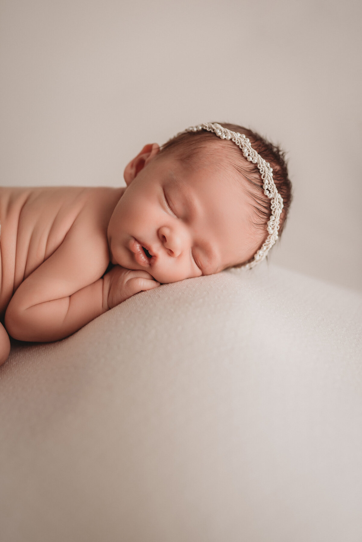 baby girl at her newborn portrait session at Marietta, GA newborn photography studio sleeping and curled up while posing for her newborn portrait