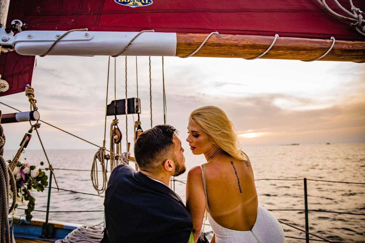 Wearing an open back wedding dress, the bride and groom pose for their Wisconsin sailboat elopement
