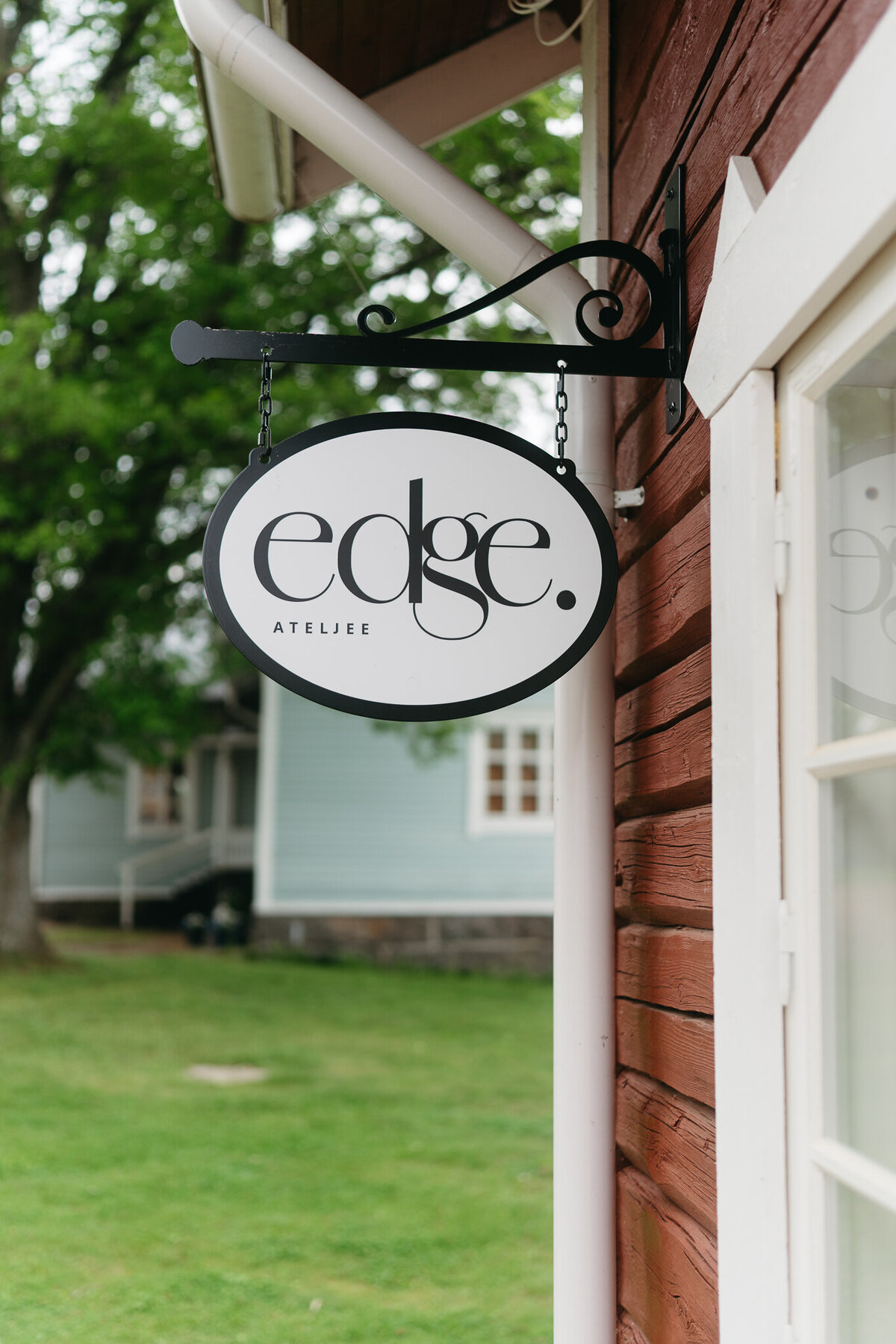 Kuvassa näkyy yrityksen logo keramiikkstudion punaista ulkoseinää vasten