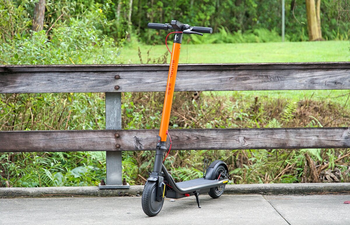 Lady walks upstairs holding Red Scoot E-3; V&D Electric Bikes