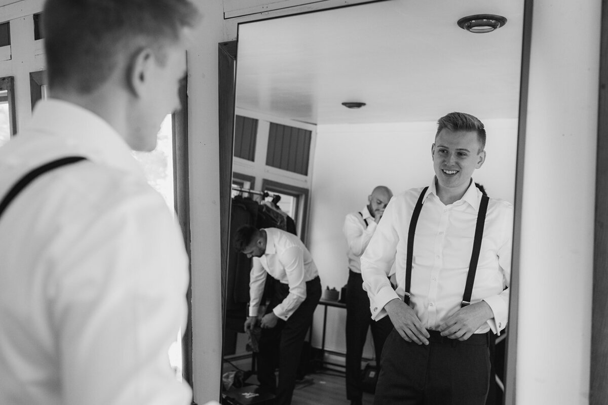 groom looks in mirror as he gets ready