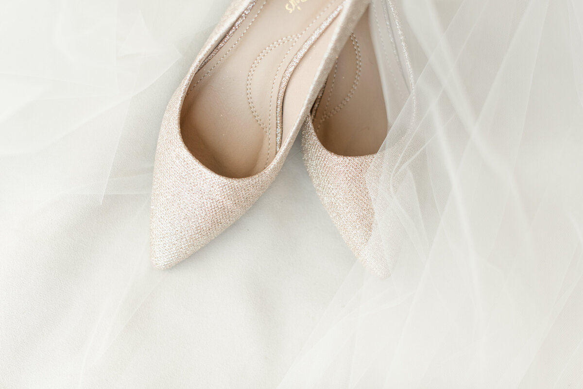 Bride's white high heel shoes displayed in a v-shape by white veil.