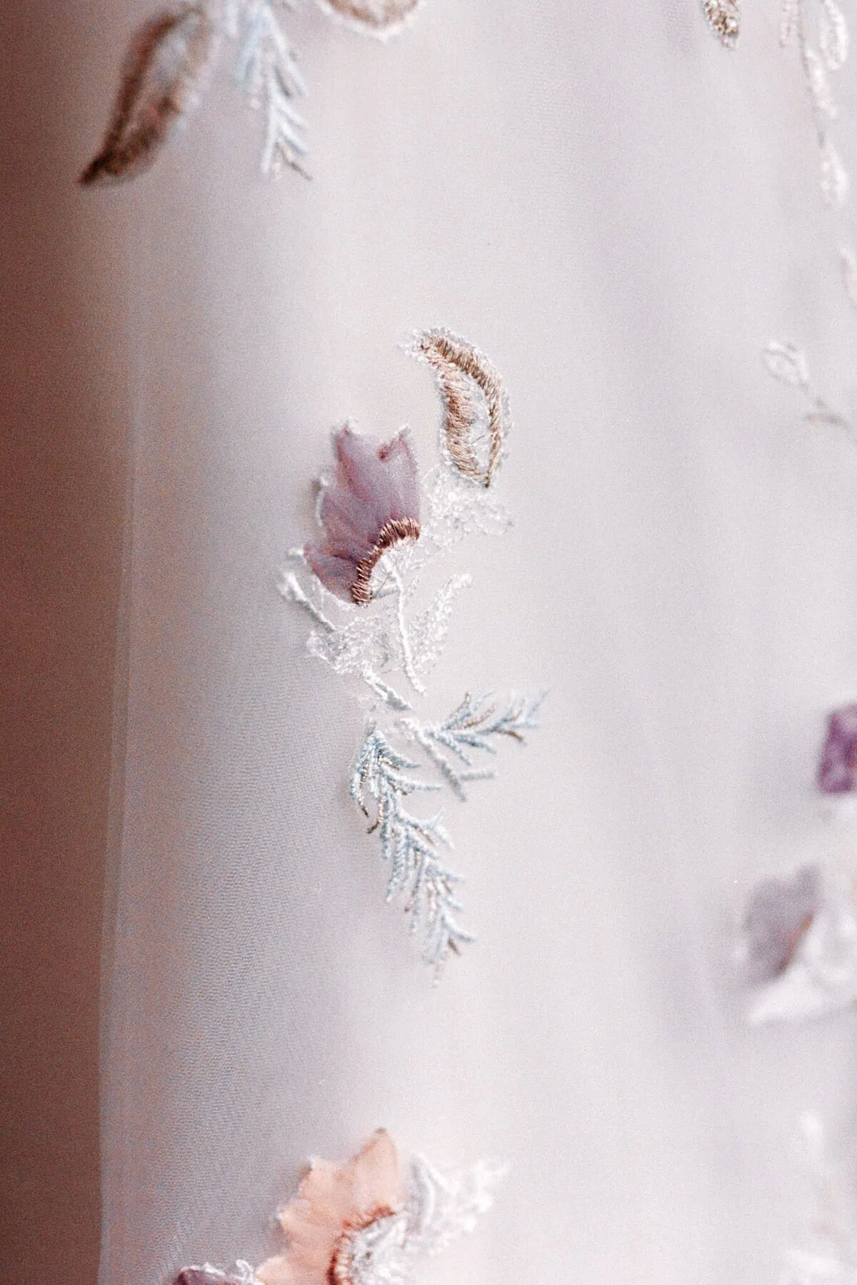 Sheer white fabric featuring delicate embroidered floral designs in soft pastel colors, including lavender, peach, and pale green—perfect for a nj wedding photographer or film photographer nj seeking dreamy, romantic backdrops.
