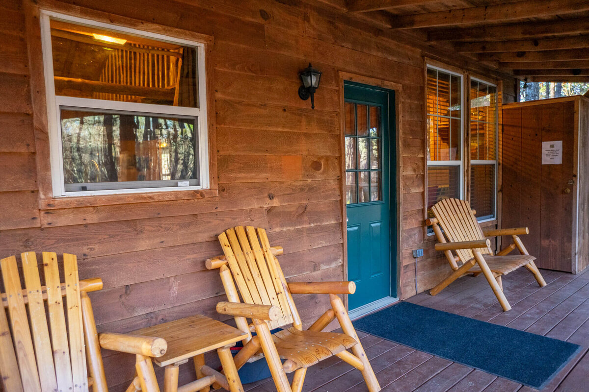 Relaxing front porch outside of cabin with adirondack chairs