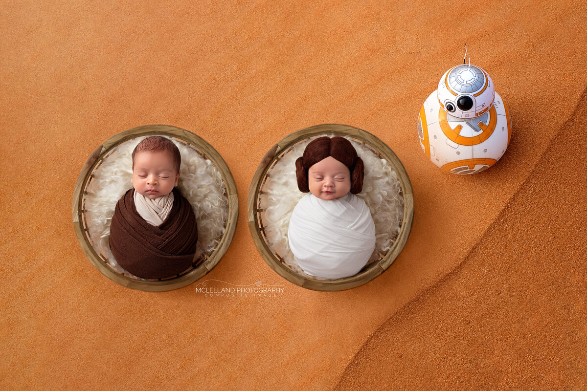 Two newborns swaddled inside brown wooden bowls on an orange Star Wars theme backdrop