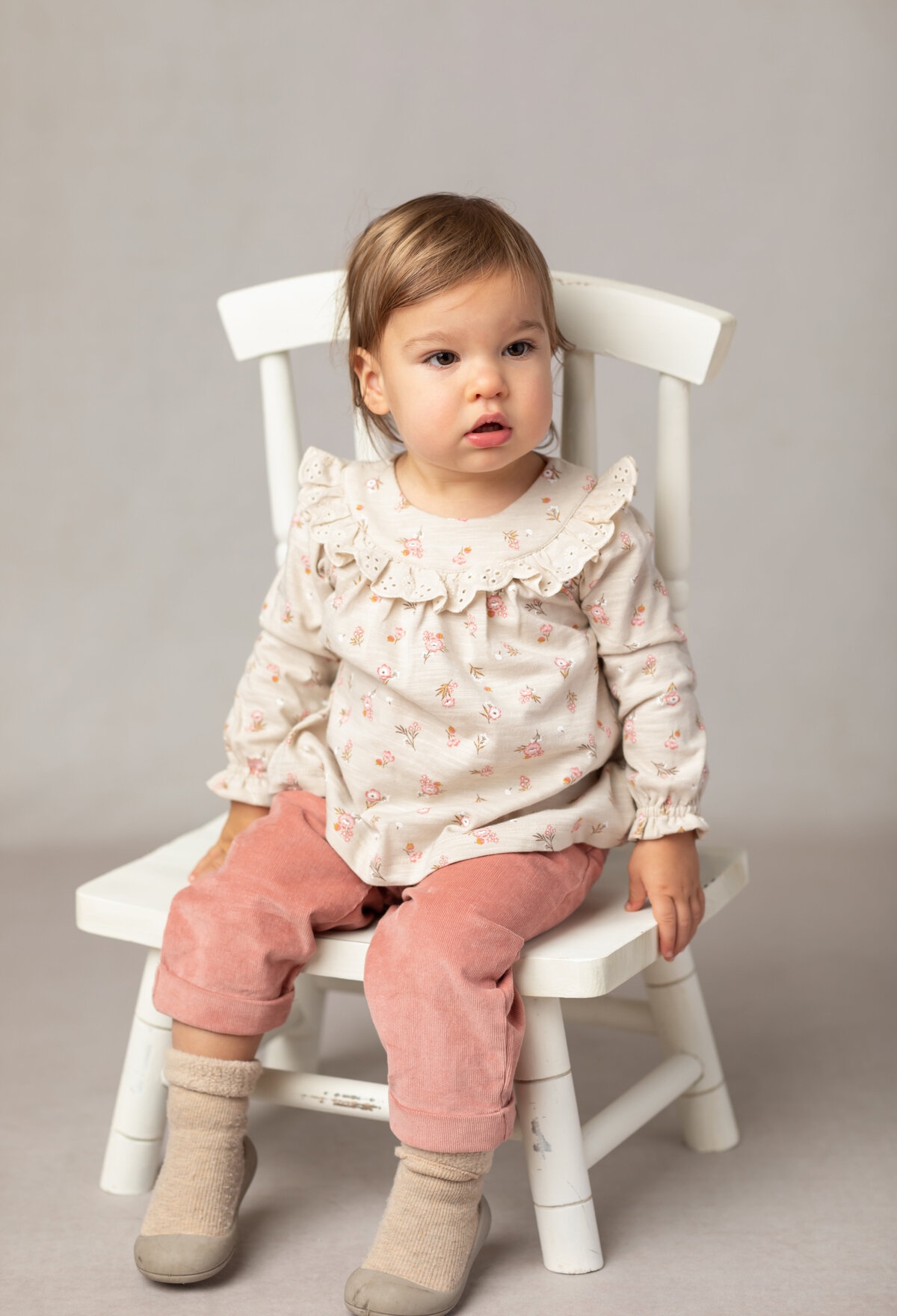 little girl sitting in white chair for studio portraits