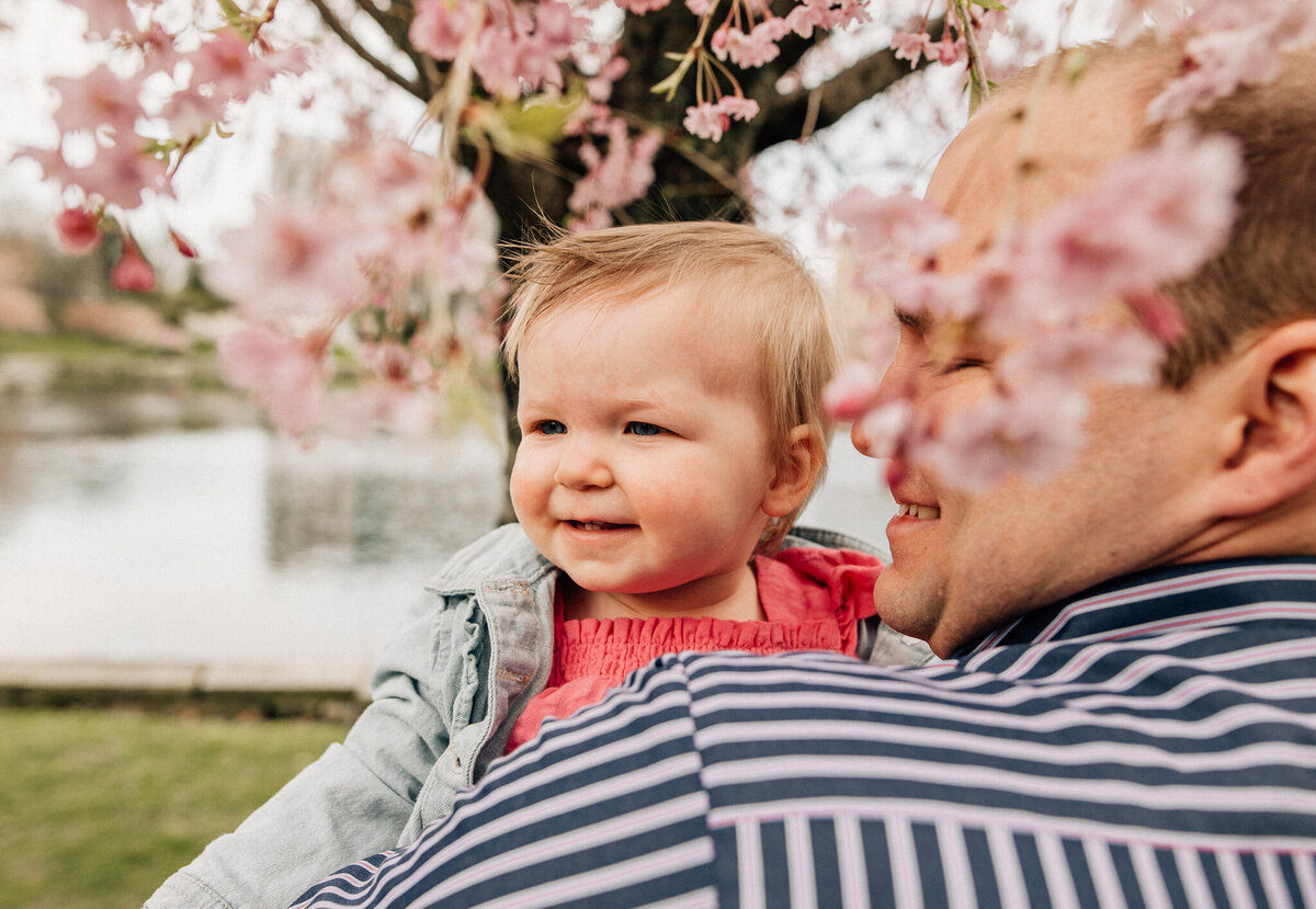Dad holds young baby outside.