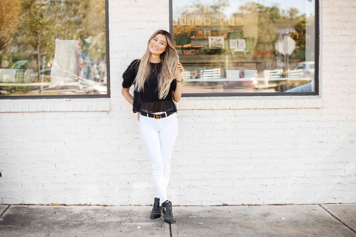 woman in black shirt in front of white brick wall