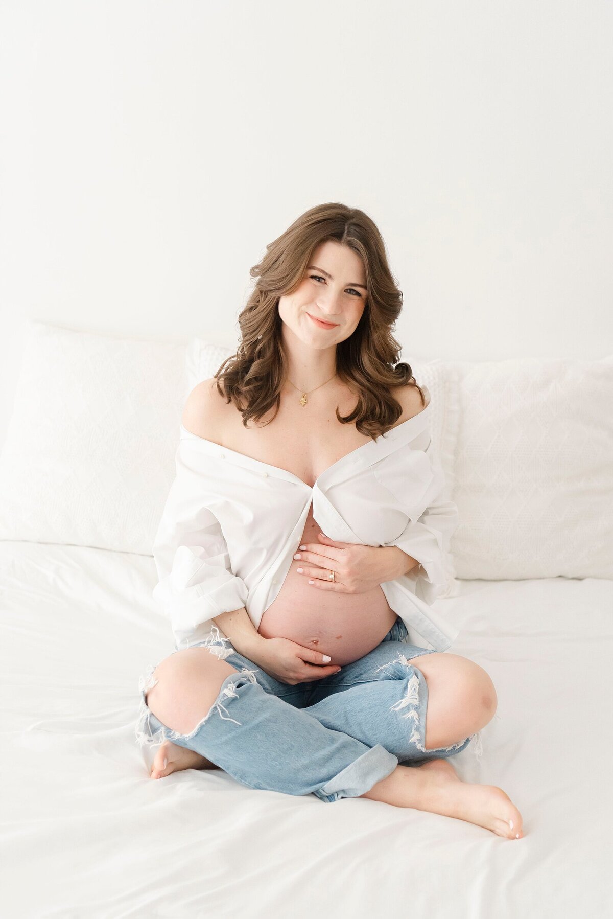 expecting mom sitting on bed by boston maternity photographer