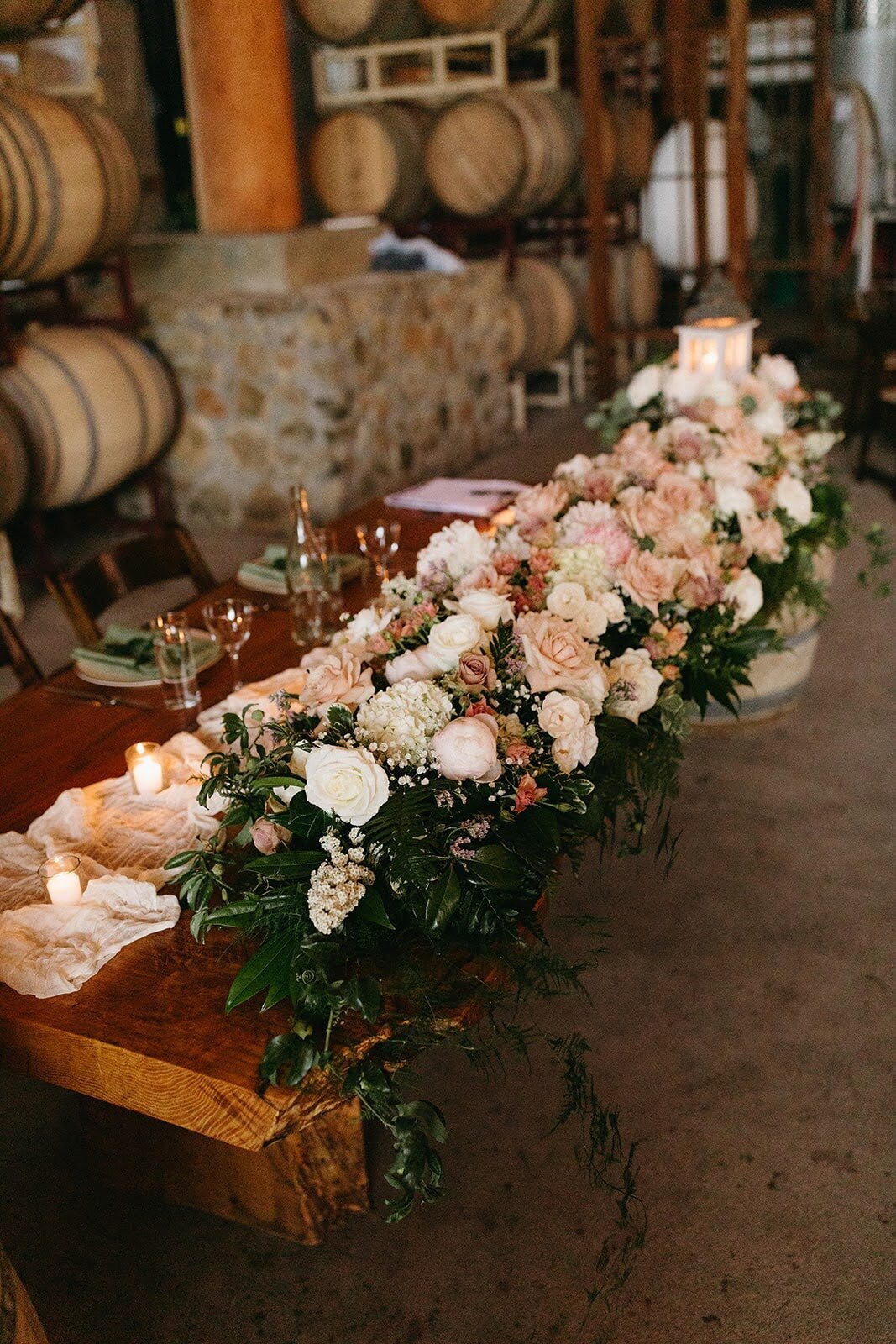 Lush, romantic floral garland by Flowers and Thyme runs along the sweetheart table at wedding reception.