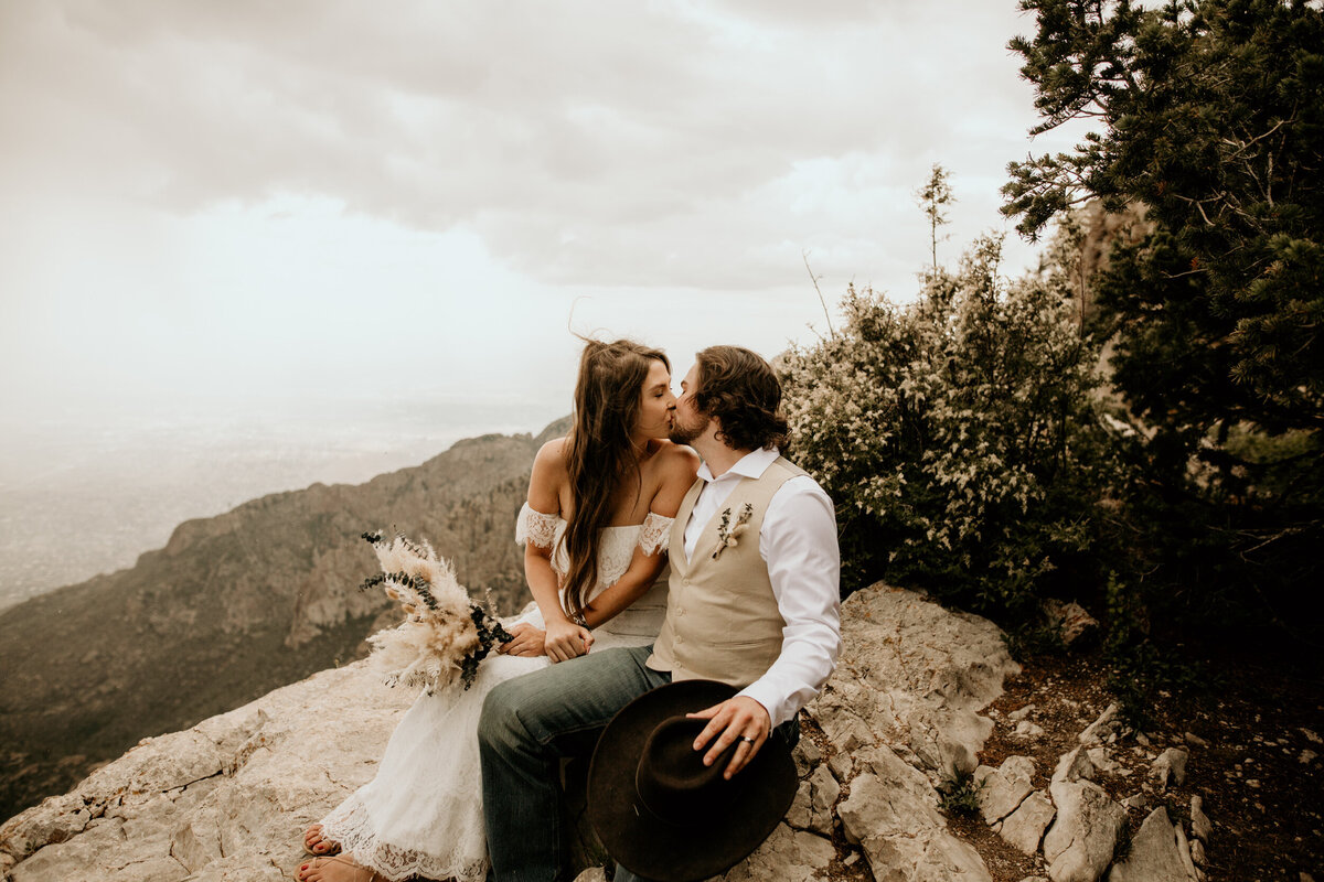 bride and groom sitting together at the Sandia Peak looking down at the city of Albuquerque