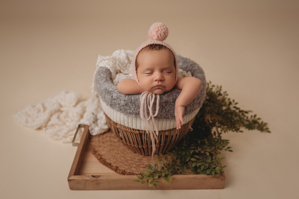 Newborn photo shoot photographed by Atlanta, Georgia newborn photographer with baby posing on neutral fabric with dainty headband on and sleeping.