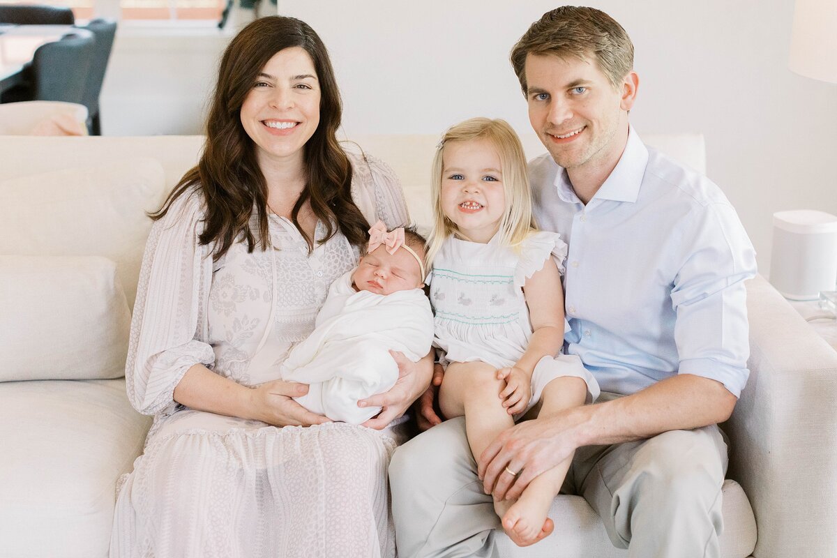 mom and dad on couch with newborn and daughter