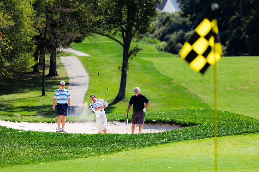People golf with a black and yellow checkered flag in the foreground.