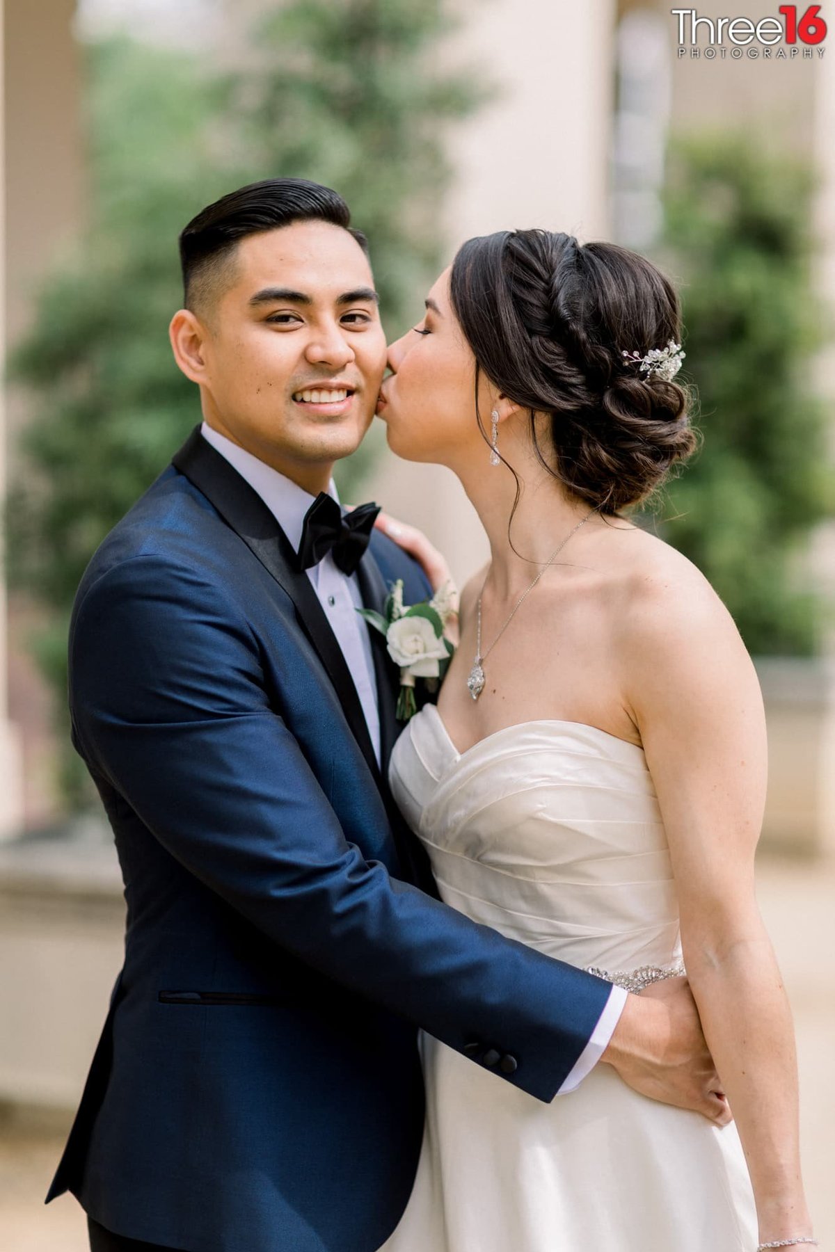 Bride gives the Groom a peck on the cheek during their wedding photos session