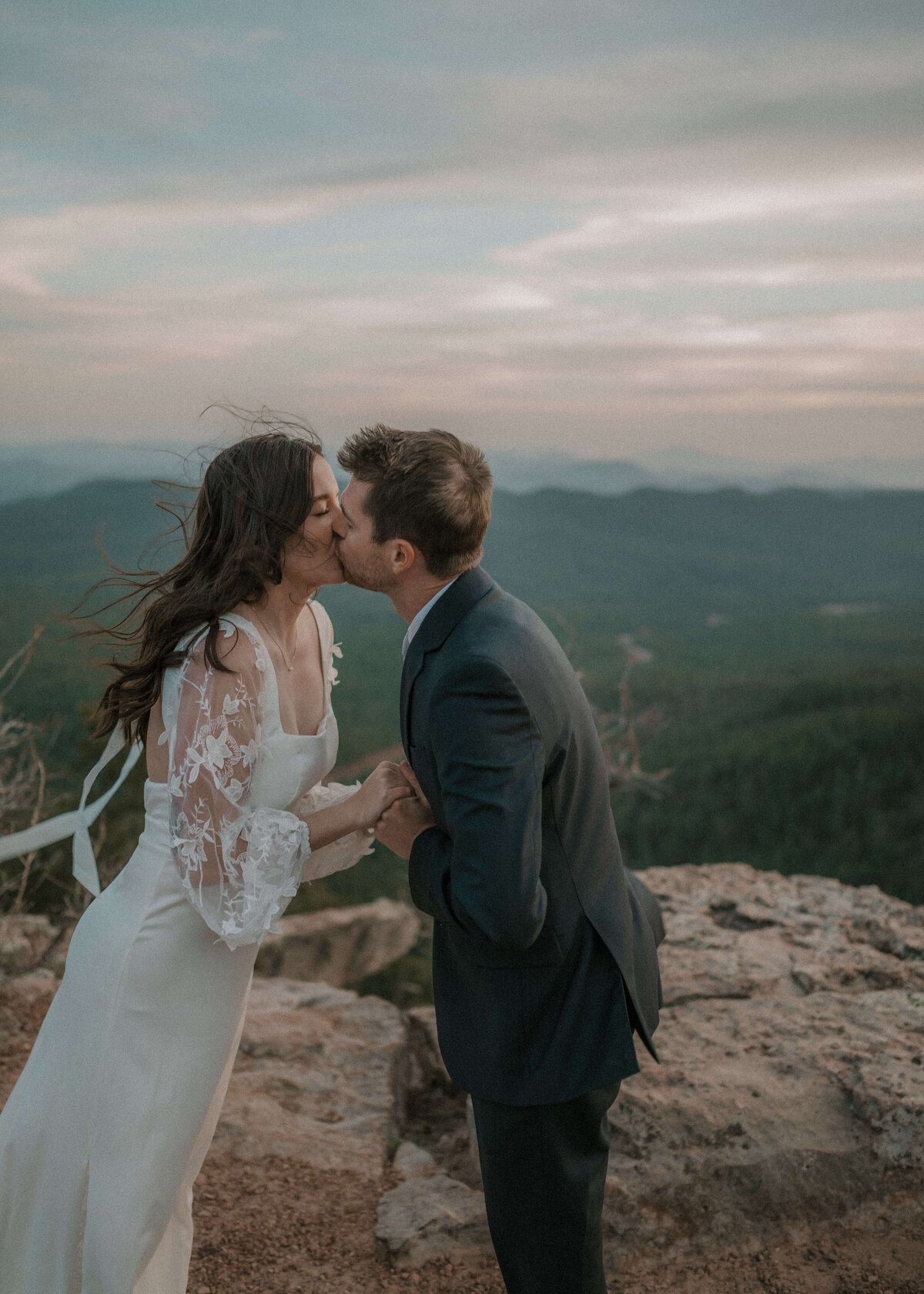 Bride and groom kissing after placing wedding bands during elopement on Mogollon Rim in Payson, Arizona