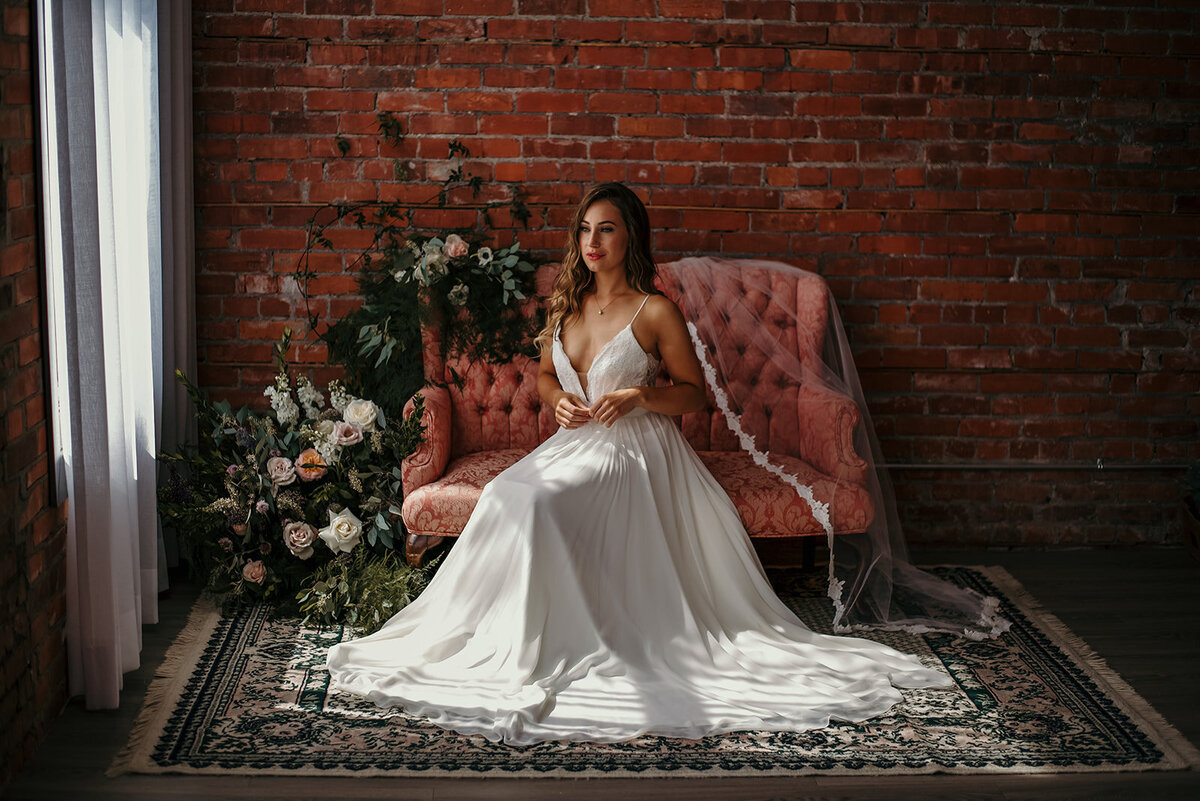 Stunning bride sitting on chair with flowers around her