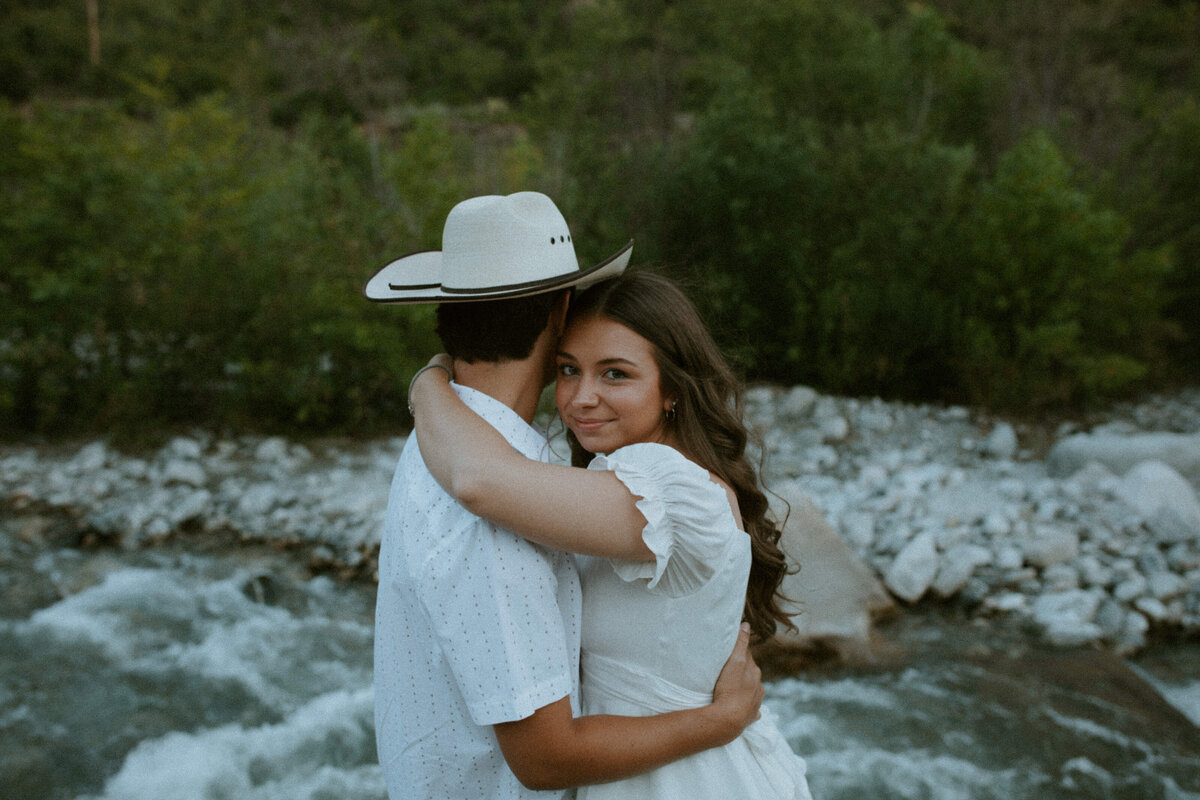 couple standing in front of river hugging