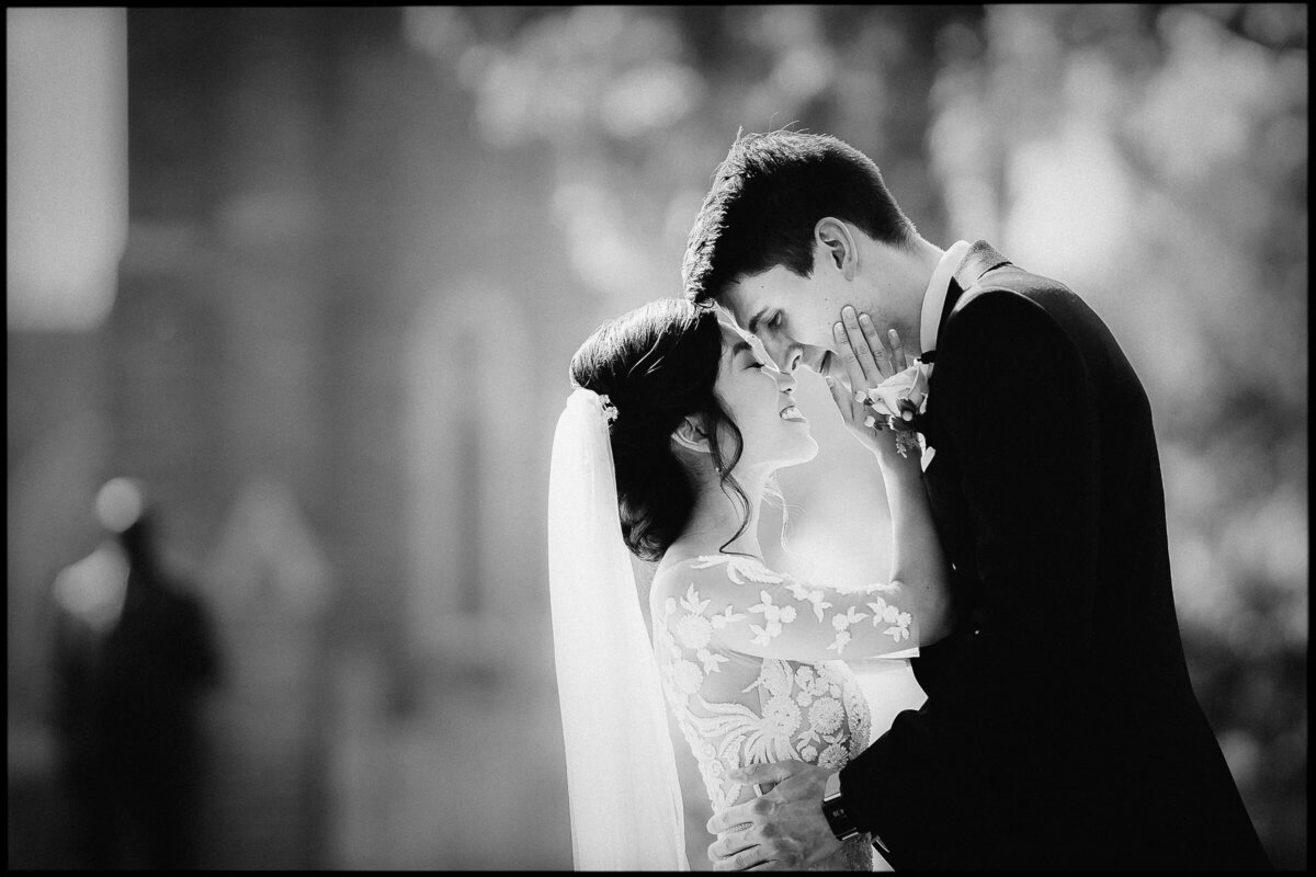 Black and white portrait of a bride and groom sharing an intimate moment, their silhouettes framed by the soft light