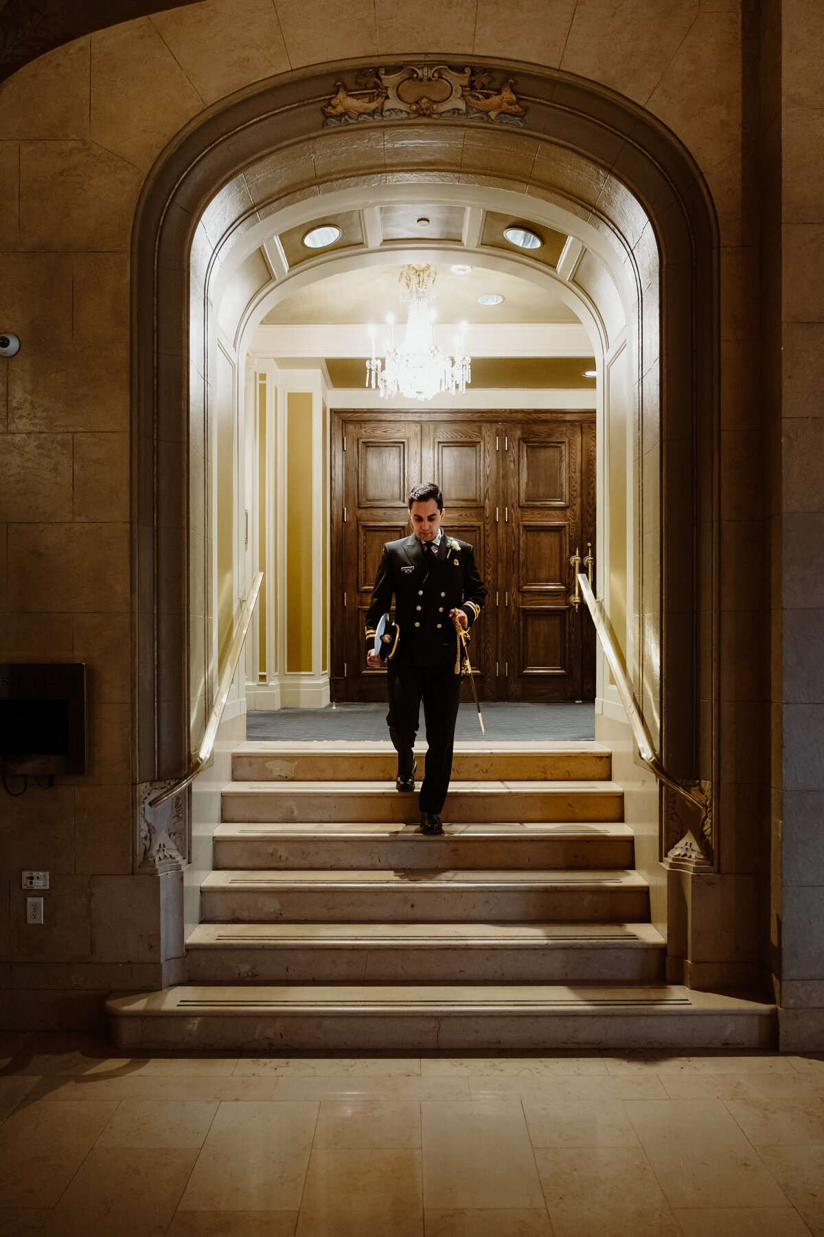 groom walking down a set of stairs in an alcove of the chateau frontenac