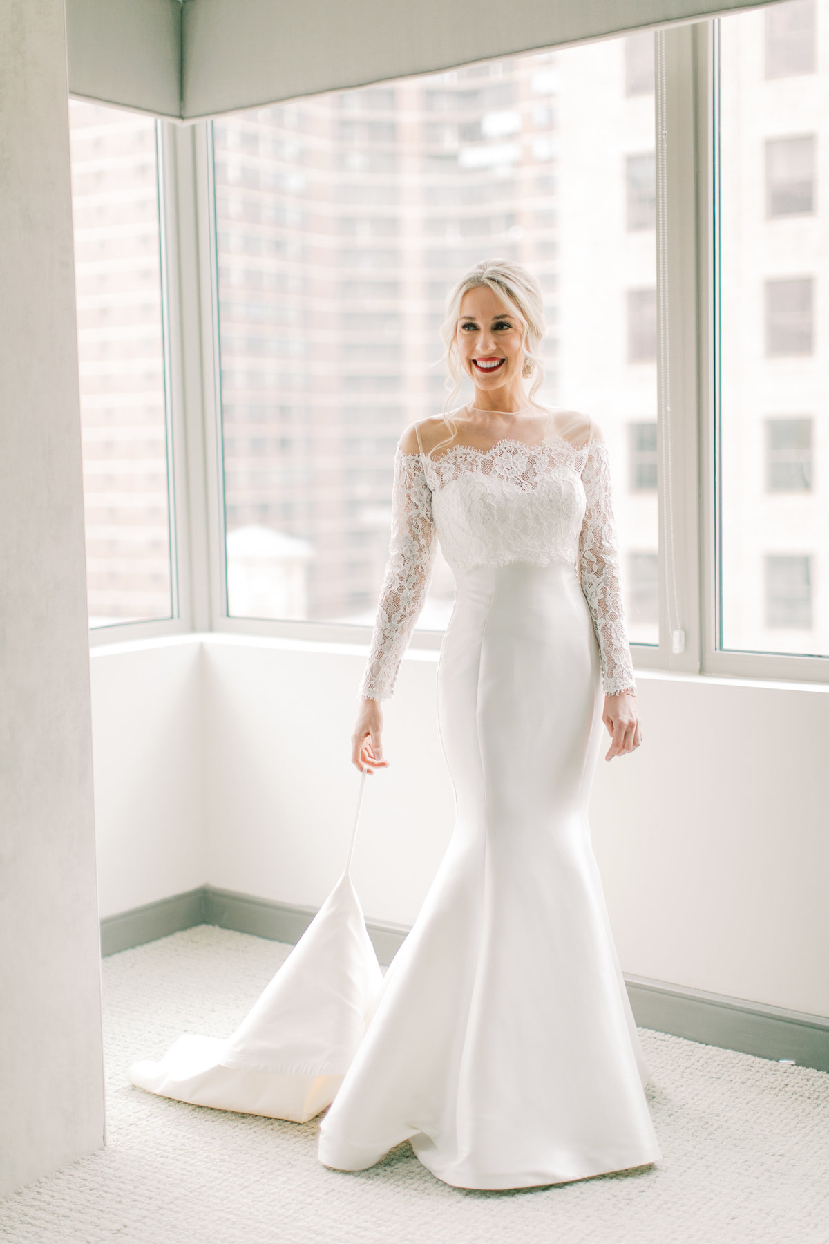 bride standing in front of windows taking bridal portraits