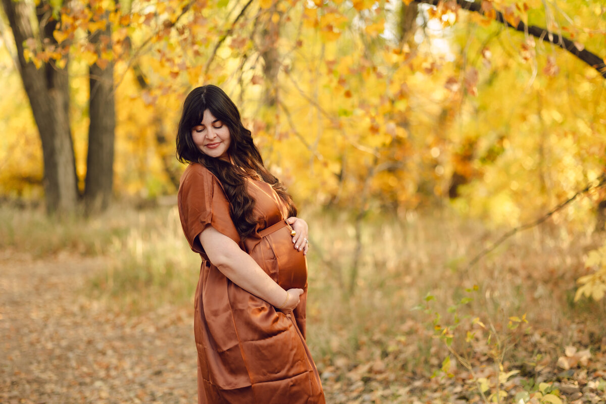 A pregnant woman poses for a photo at Riverbend Ponds in Fort Collins, Colorado.