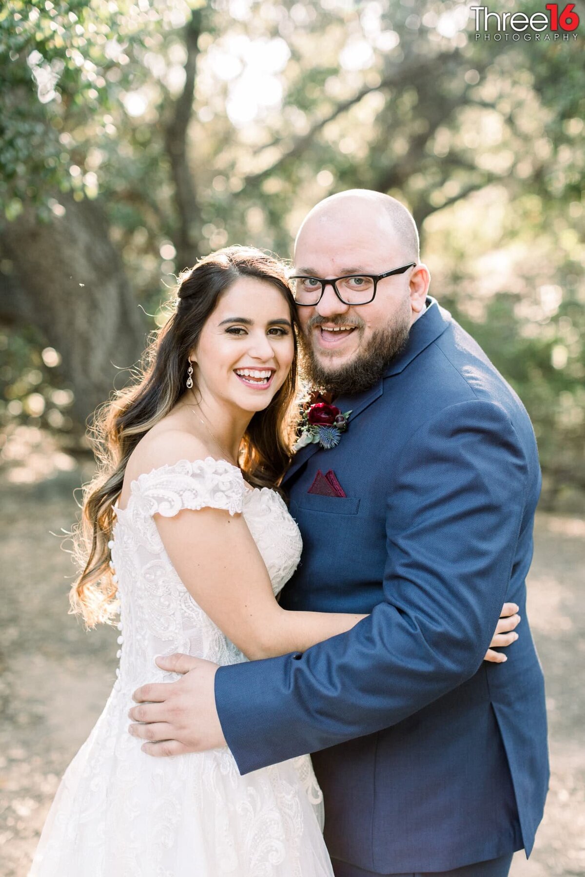 Bride and Groom embrace each other as they look to the wedding photographer splashing big smiles