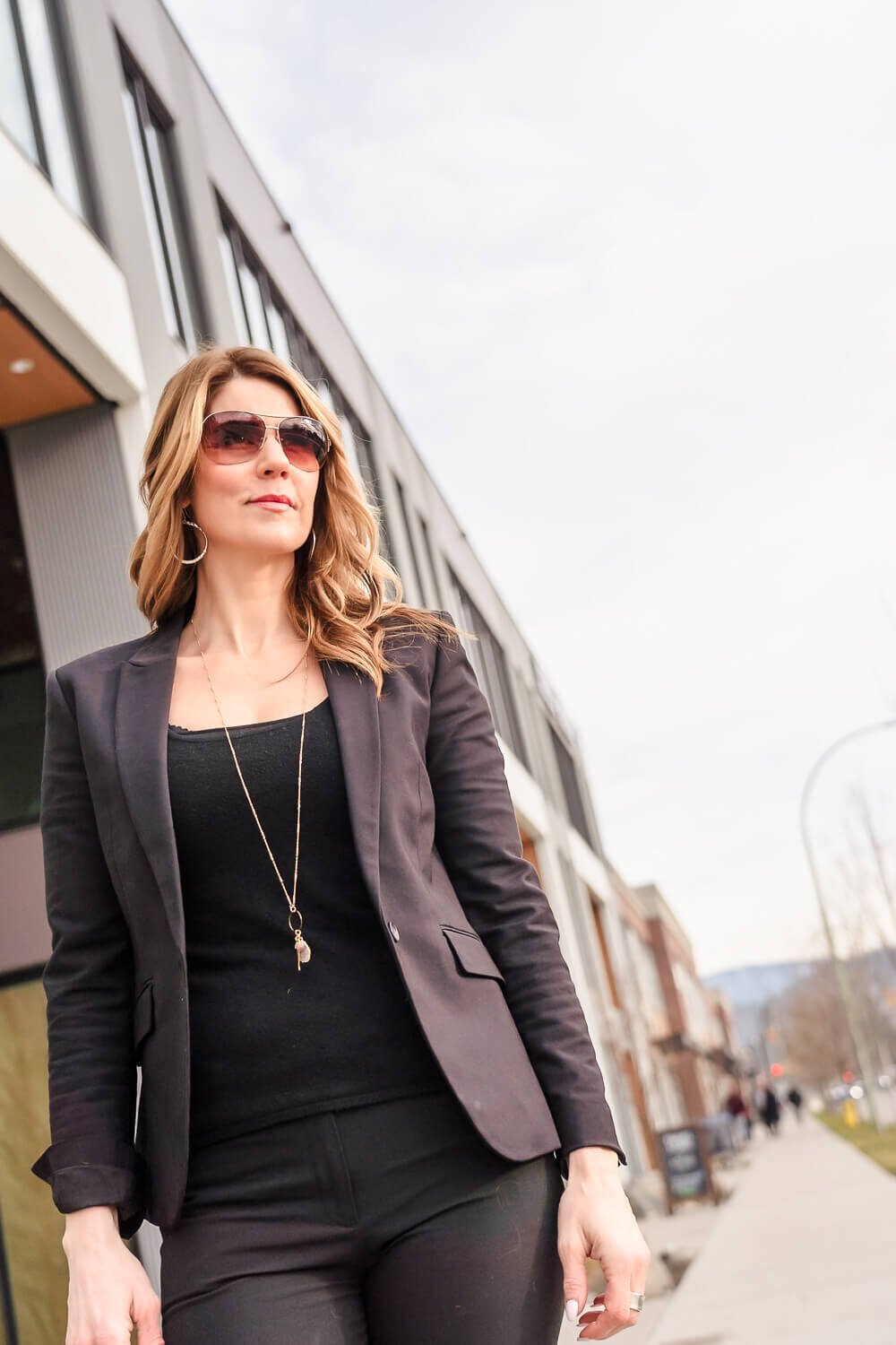 Entrepreneur walking outdoors wearing sunglasses and black jacket in urban setting