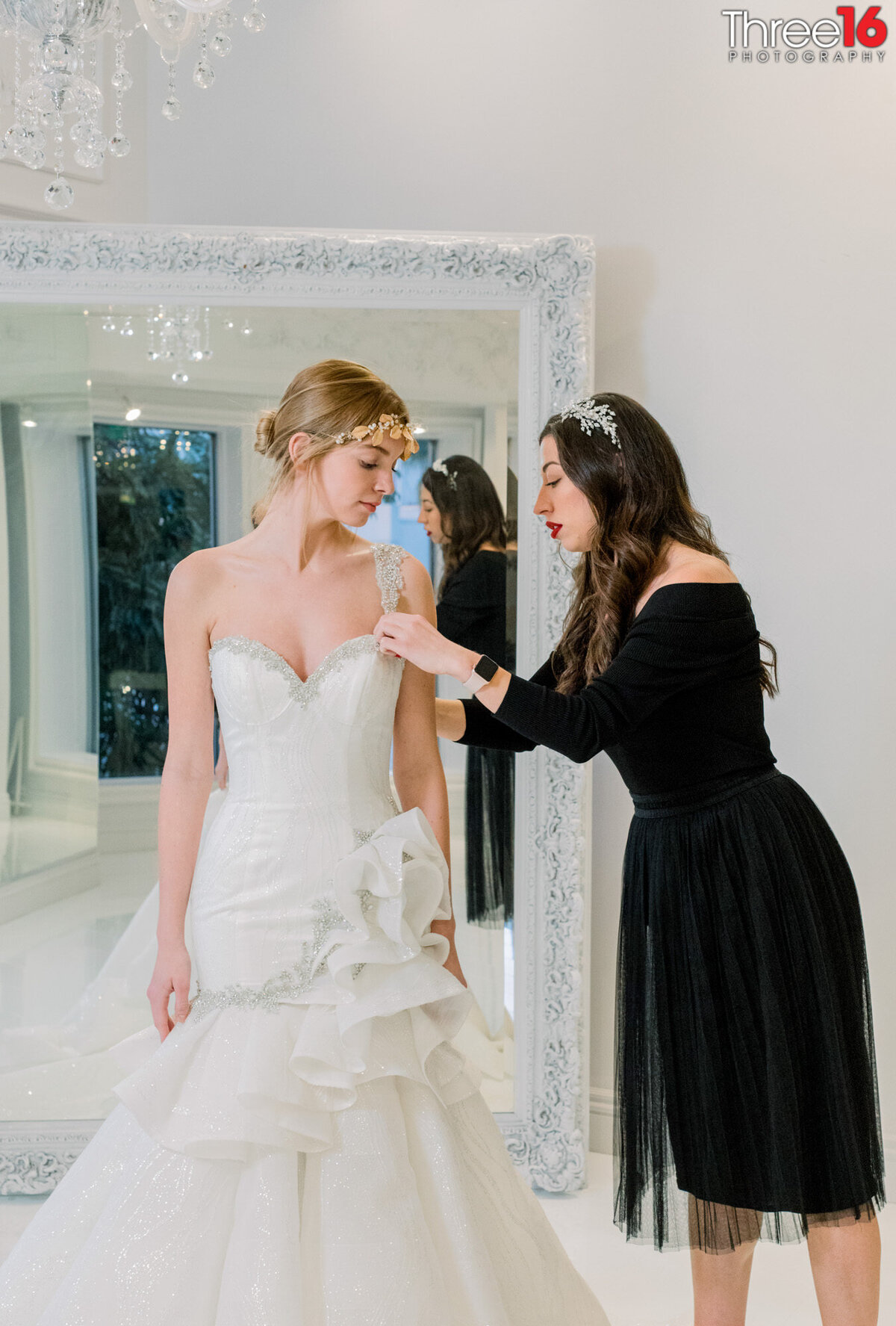 Bride to be gets fitted for her dress by bridal shop employee