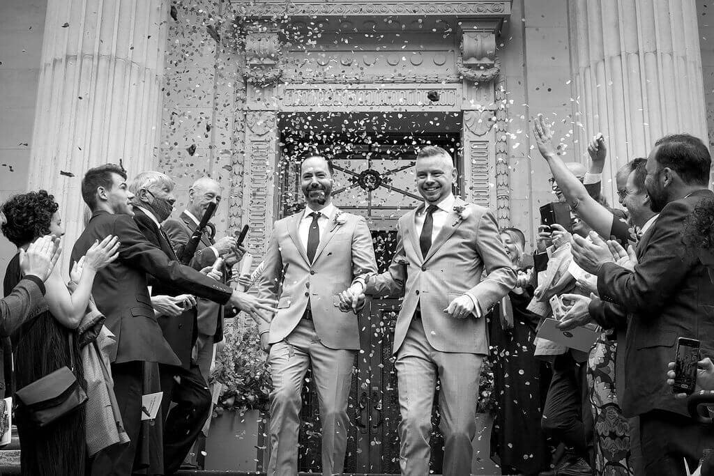 Groom and groom holding hands walking down steps of Marylebone Town Hall