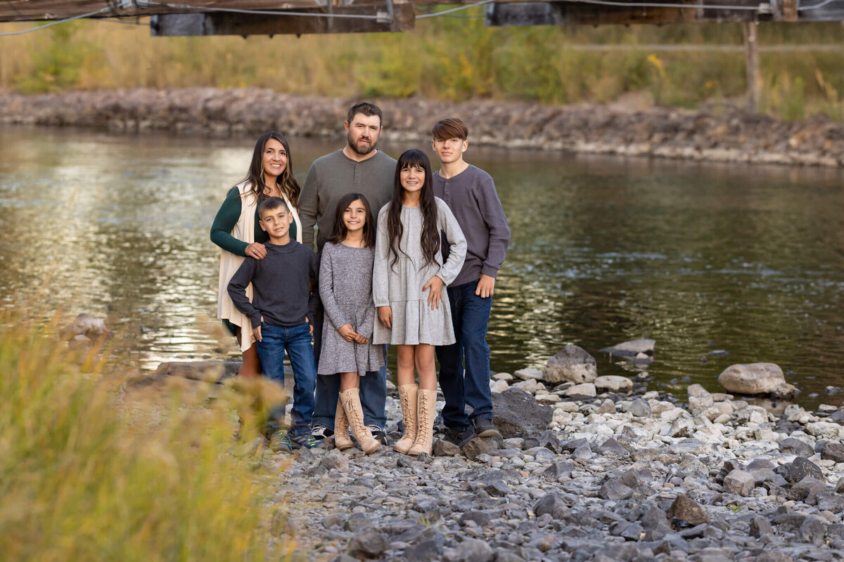 family of six standing together by a river